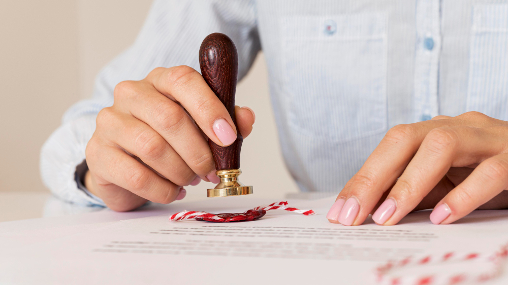 Person sealing a legal document with a wooden wax stamp.