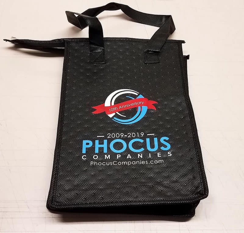 Black reusable tote bag with Phocus Companies anniversary logo printed.