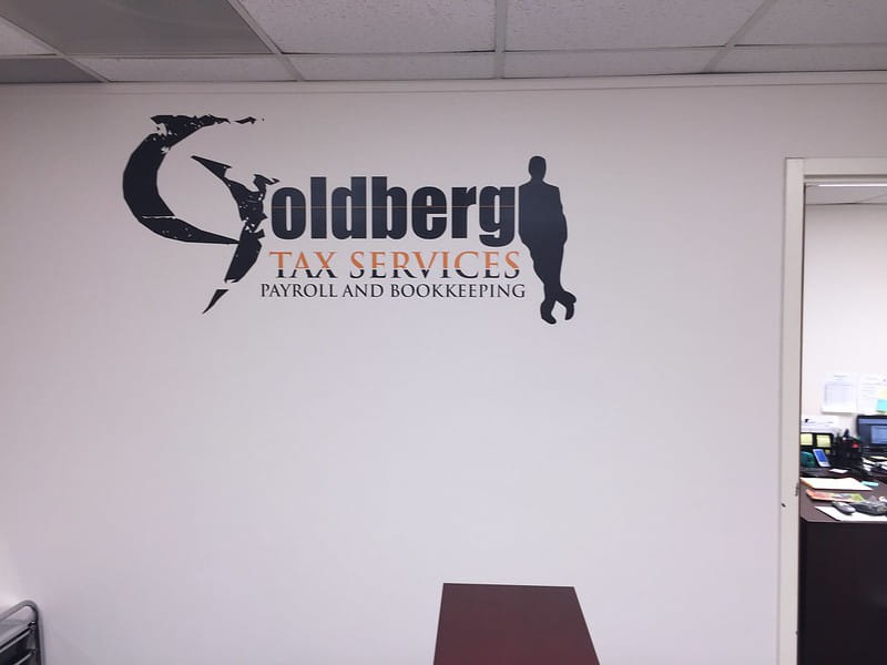Office wall sign for Goldberg Tax Services payroll and bookkeeping.