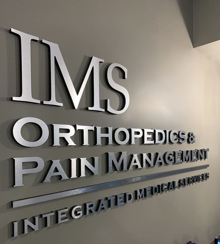 IMS Orthopedics & Pain Management silver logo sign on wall.