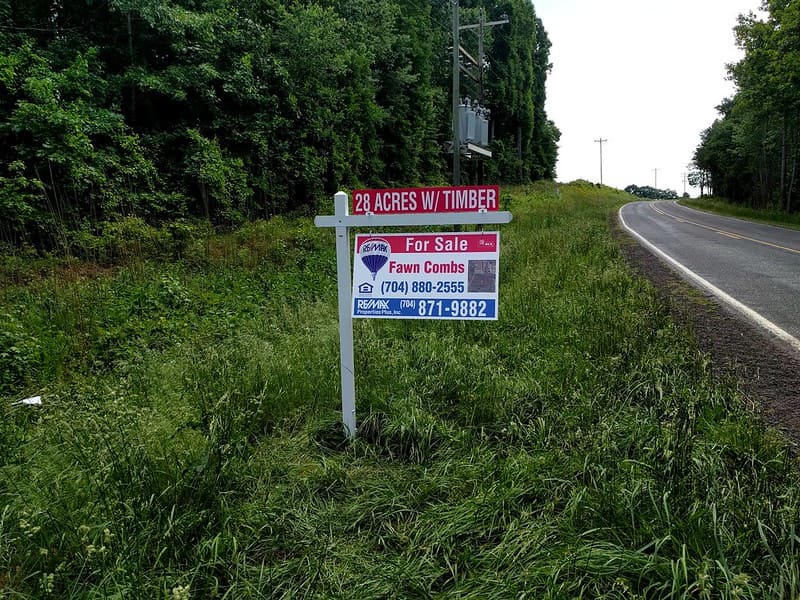 Real estate sign advertising 28 acres with timber for sale.