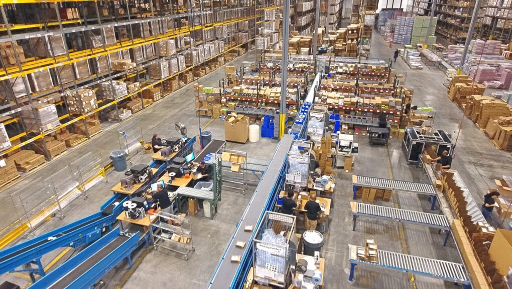 Large distribution warehouse with conveyor belts and organized storage racks.